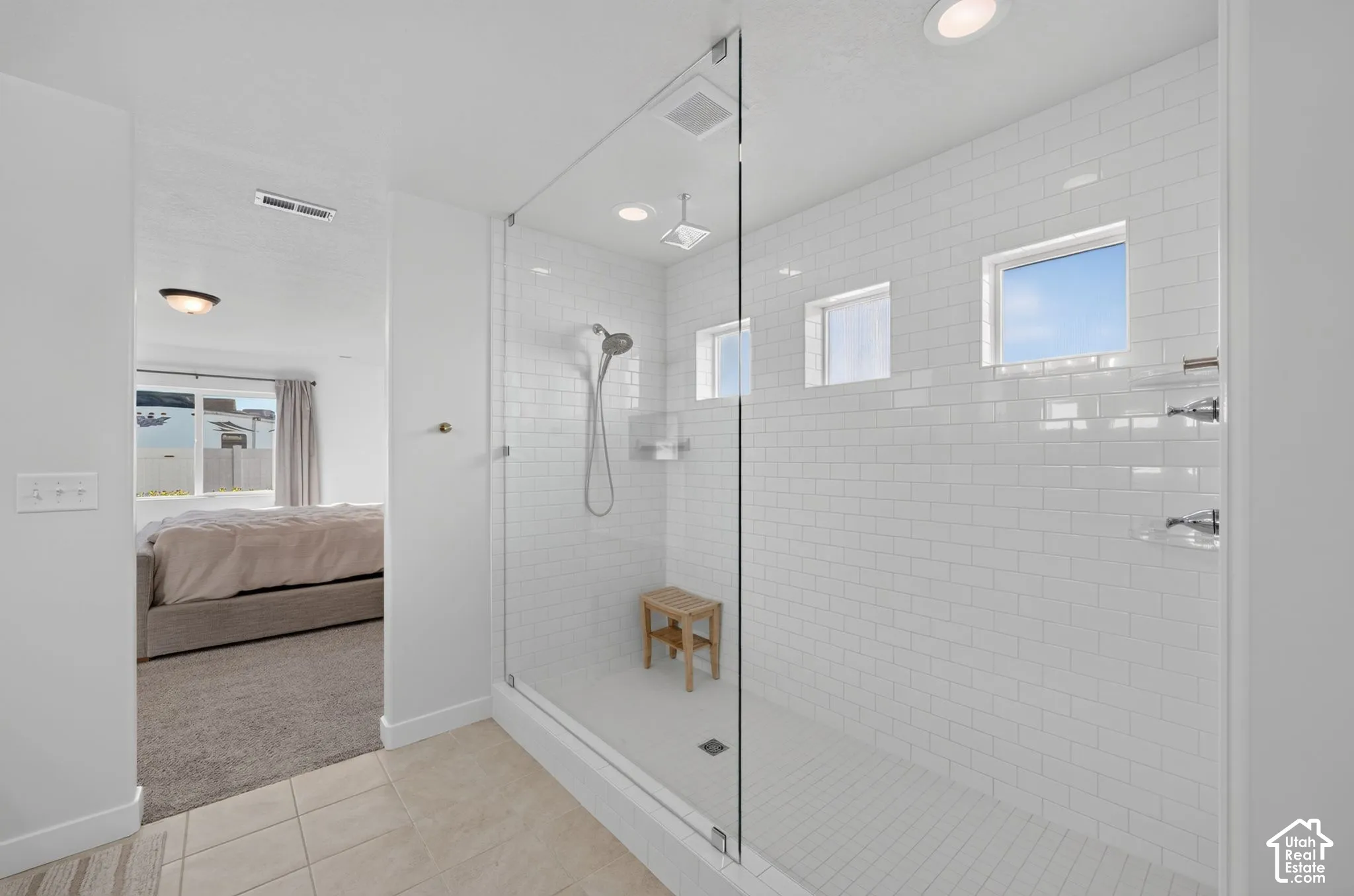 Spacious shower with white subway tile, clear glass enclosure, and multiple windows