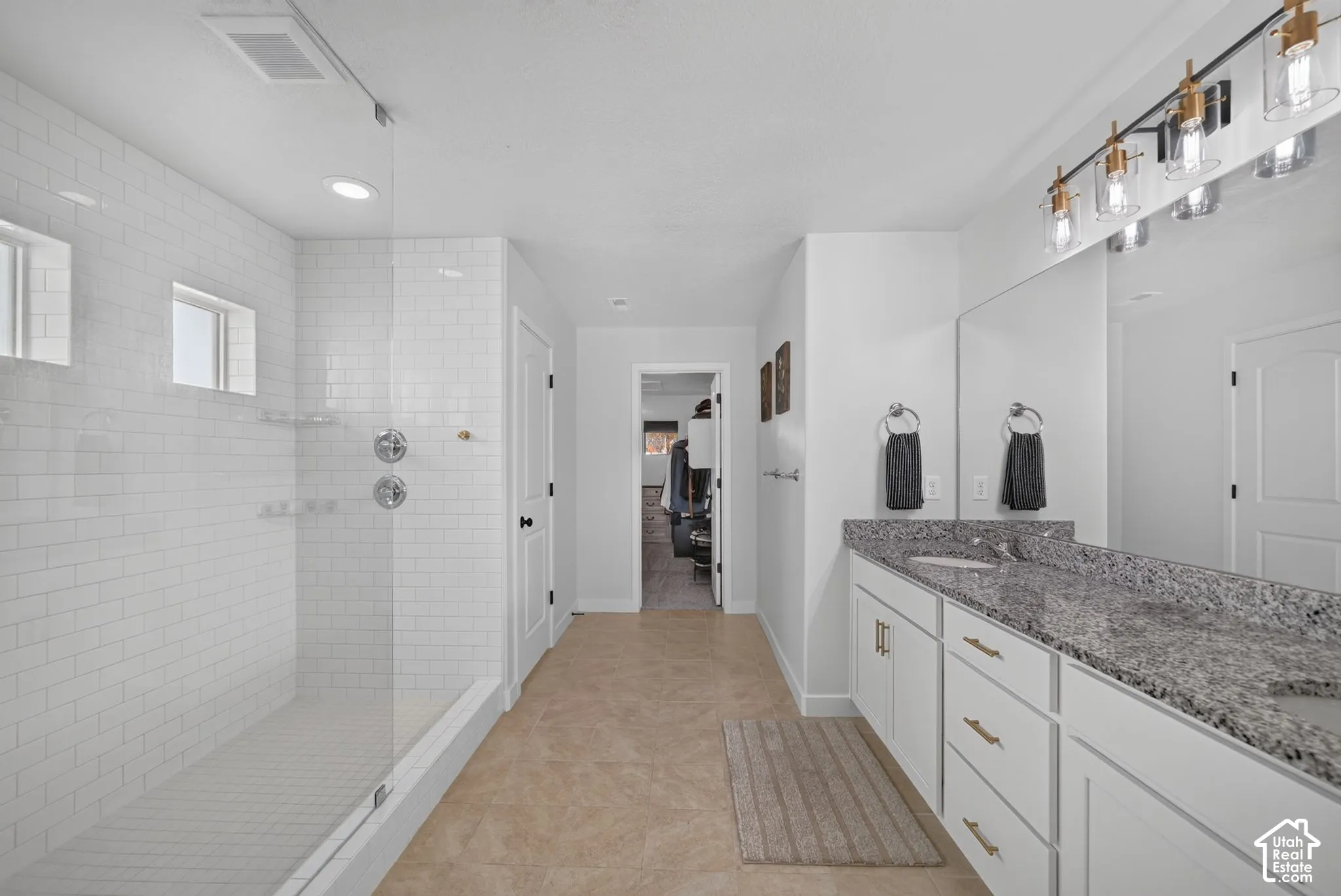 Walk-in shower with subway tile surround, clear glass enclosure, and recessed lighting