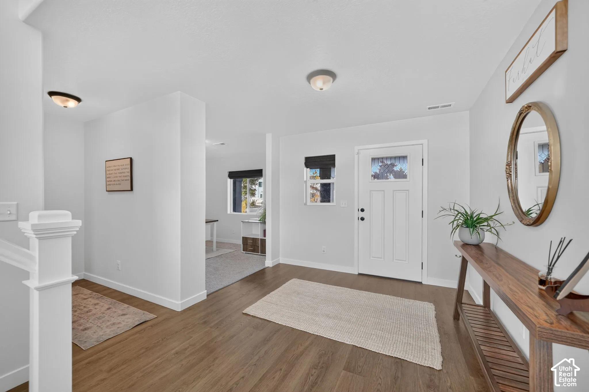 Entryway featuring wood-finish flooring, a paneled entry door with frosted glass, and a side window with dark roller shades
