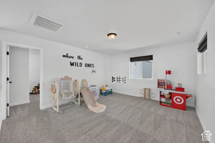 Spacious room with light gray carpeting, neutral white walls, and a recessed ceiling light