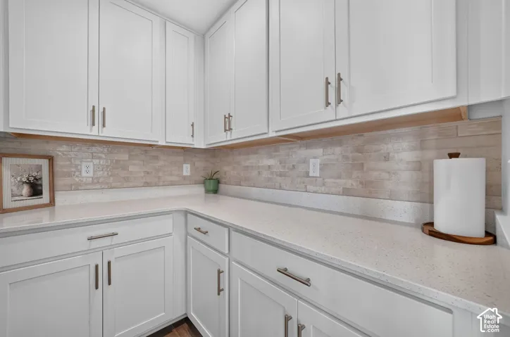 Bright kitchen featuring white shaker-style cabinetry with brushed nickel hardware, quartz countertops, and a subway tile backsplash in neutral tones