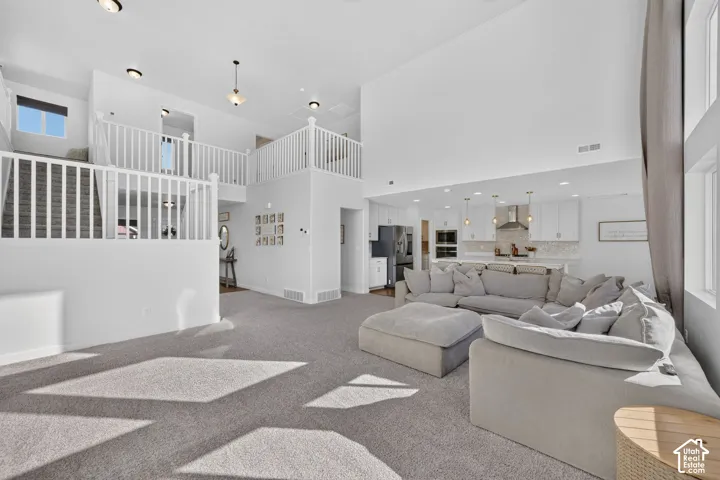 Vaulted ceilings, open concept design, white cabinetry, stainless steel appliances, and a two-story staircase with white railings