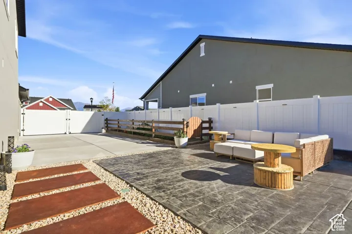 Stamped concrete patio with a white privacy fence, gravel accents, and a concrete pathway