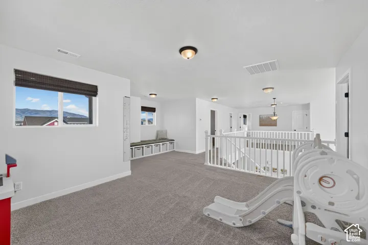 Spacious bonus room featuring neutral carpeting, abundant natural light from large windows with mountain vistas, recessed ceiling lighting, and built-in white cabinetry