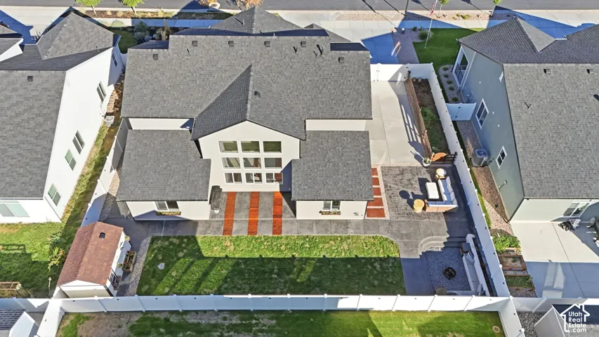 Expansive backyard featuring a manicured lawn, concrete patio with integrated brickwork, a dedicated fire pit area, and a storage shed