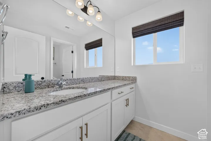 White vanity with bronze hardware, a gray speckled countertop, and a built-in sink