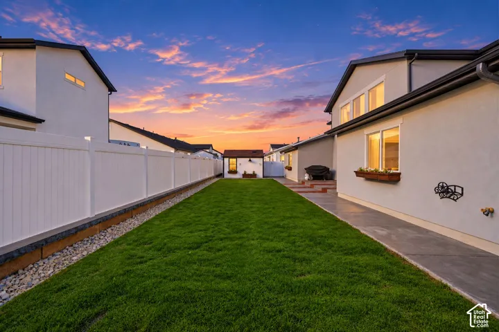 Expansive grassy lawn with a concrete walkway and white perimeter fencing