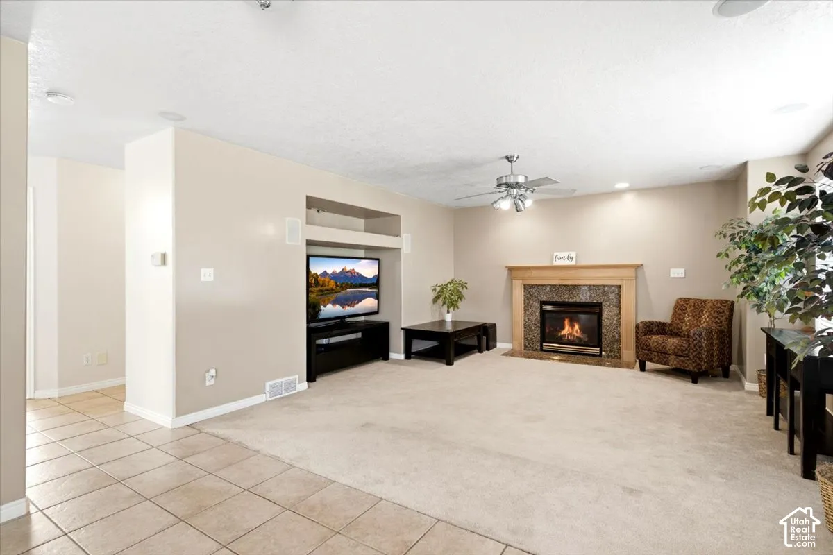 Living area featuring a fireplace with a stone surround and wood mantel, a ceiling fan, recessed lighting, and a built-in media niche
