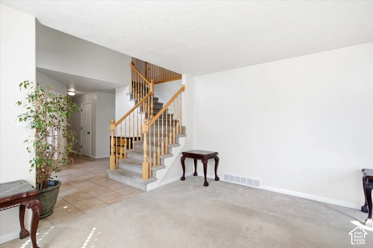 Two-story staircase with wood banister and carpeted treads