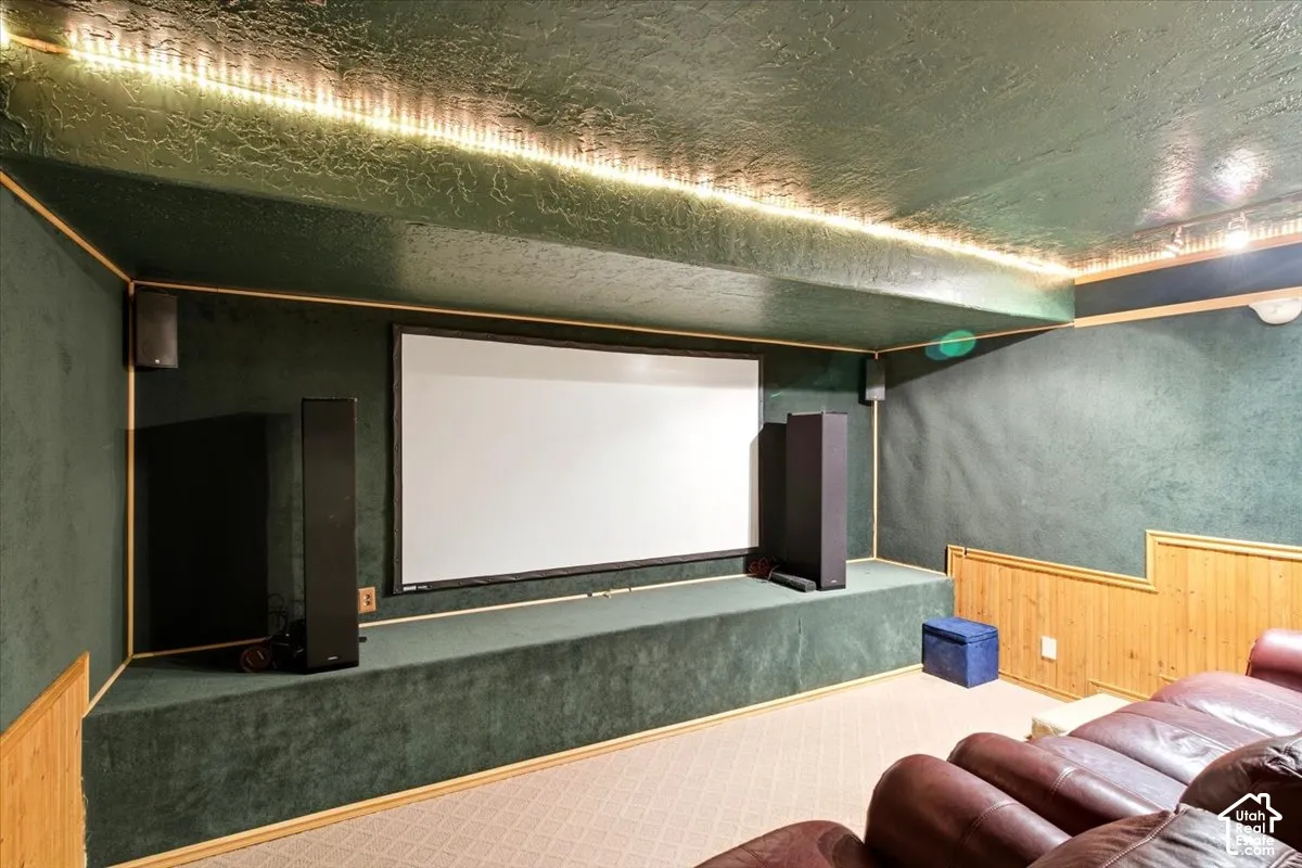 Dedicated media room featuring a large projector screen, upholstered walls, and recessed ceiling lighting