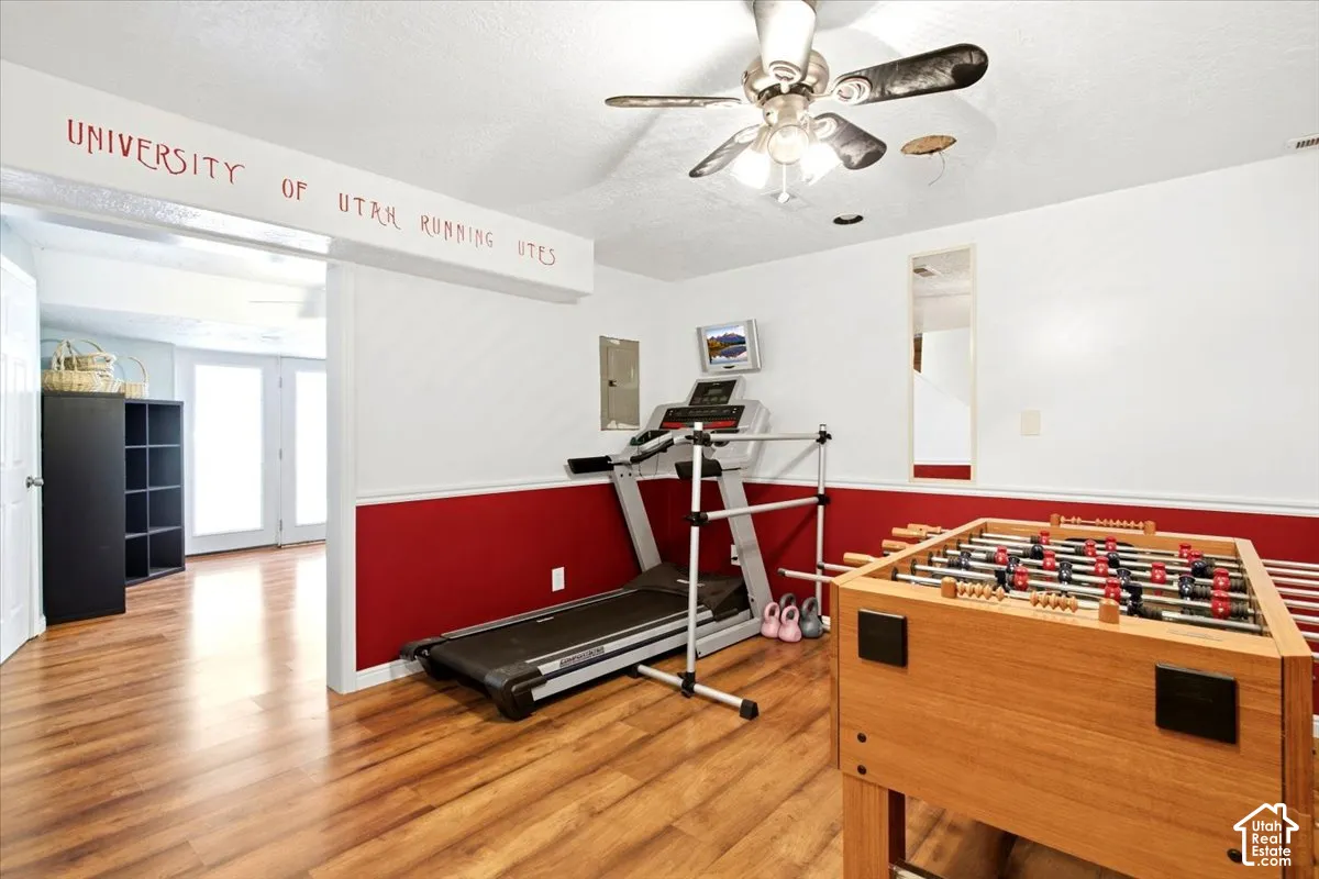 Wood-finish flooring throughout, two-tone wall treatment, and a ceiling fan