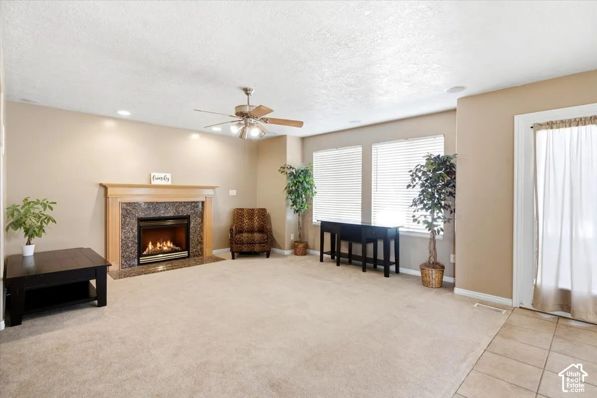 Carpeted living area with a fireplace featuring a wood mantel and stone surround