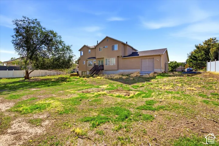 Expansive backyard featuring a large tree, a partial white privacy fence, and direct access to the home's exterior deck