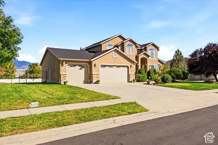 Stucco exterior with stone accents, multiple arched windows, a two-car garage, and an additional single-car garage