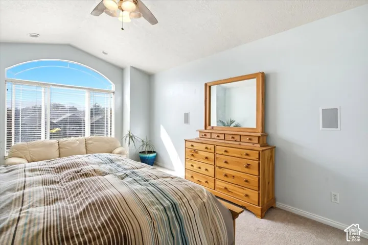 Vaulted ceiling with a ceiling fan and recessed lighting, large arched window, and wall-mounted speakers