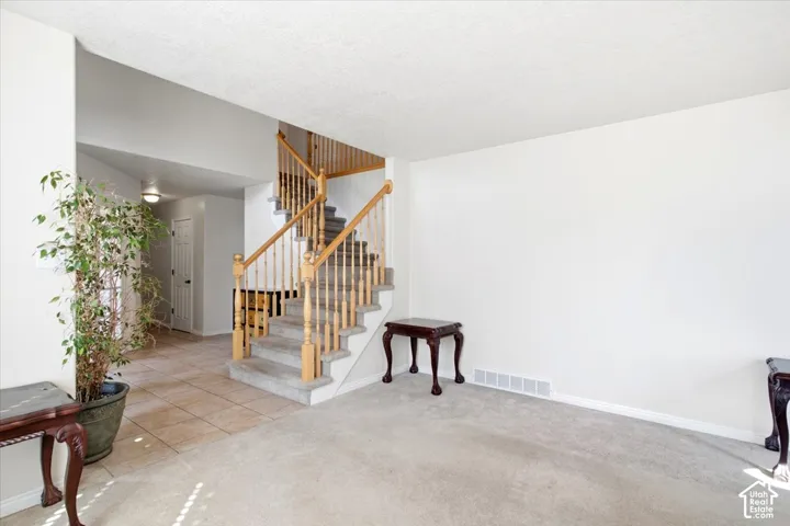 Two-story staircase with wood banister and carpeted treads