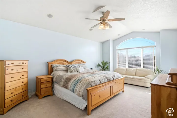 Vaulted ceiling with a ceiling fan, recessed lighting, and an arched window