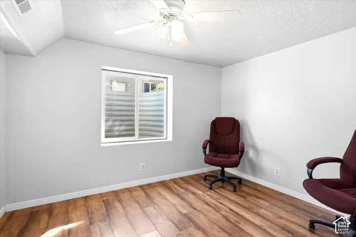 Wood-finish flooring, white walls, and a ceiling fan