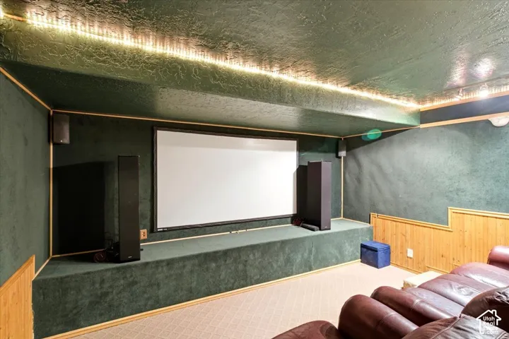 Dedicated media room featuring a large projector screen, upholstered walls, and recessed ceiling lighting