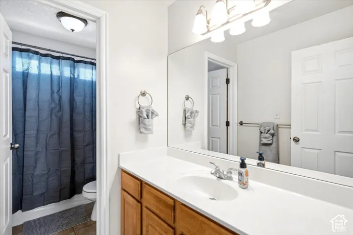 Bathroom featuring a single vanity with wood-finish cabinetry, a large mirror, a chrome faucet, and overhead lighting