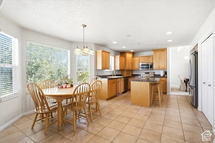 Kitchen featuring wood cabinetry, stainless steel appliances, a kitchen island with seating, and tile flooring