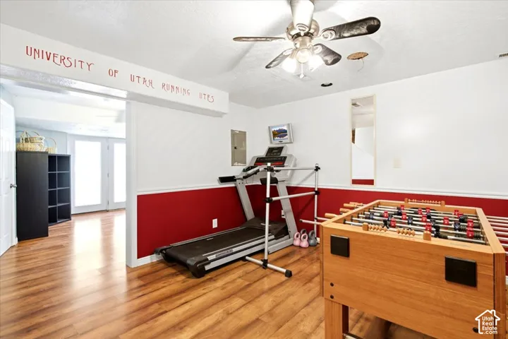 Wood-finish flooring throughout, two-tone wall treatment, and a ceiling fan