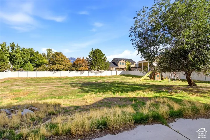 Expansive lot featuring a mature tree, concrete patio, and white privacy fencing