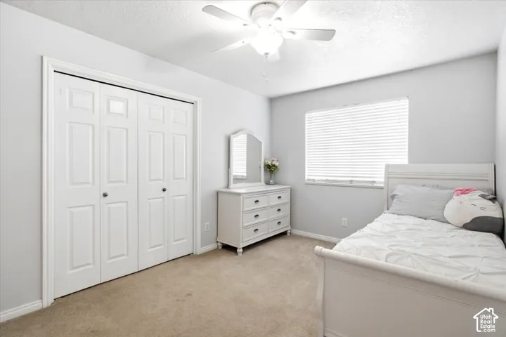 Textured ceiling with a ceiling fan, light-toned walls, and carpet flooring