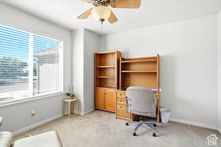 Recessed window with horizontal blinds, overhead ceiling fan with light fixture, light neutral wall paint, and carpeting
