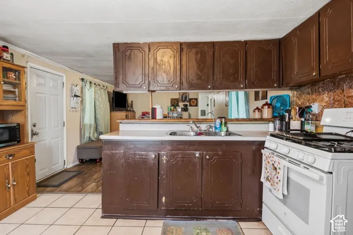 Kitchen featuring wood-finish cabinetry, white countertops, a built-in sink, and white tile flooring