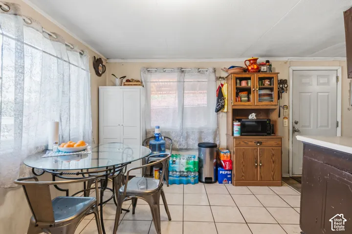 Tile flooring, white paneled door, built-in wooden cabinet, and multiple windows