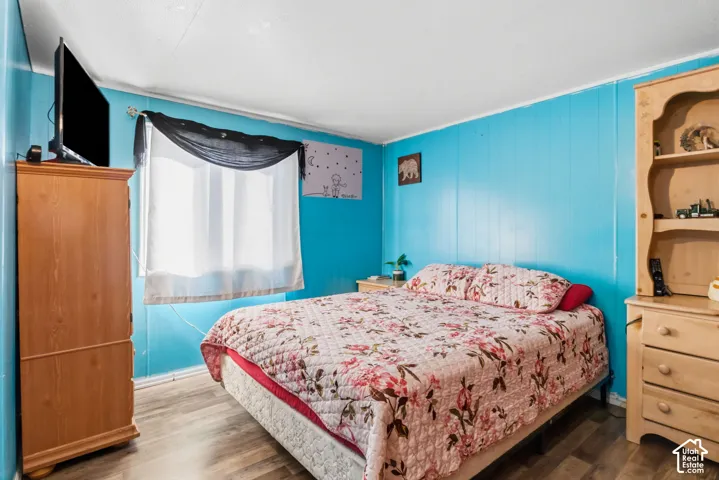 Wood-finish flooring, paneled walls, and a window with white trim