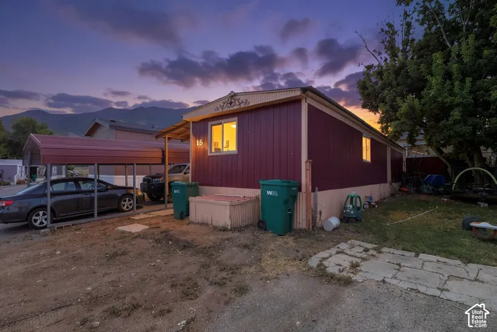 Metal carport structure, mountain backdrop, mature tree, window with trim, exterior siding