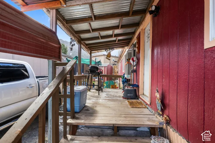 Covered porch featuring a wood deck, wood railing, and corrugated metal roof
