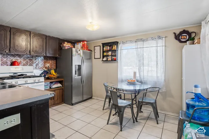 Kitchen featuring upper and lower cabinetry, white tile flooring, backsplash, and a window