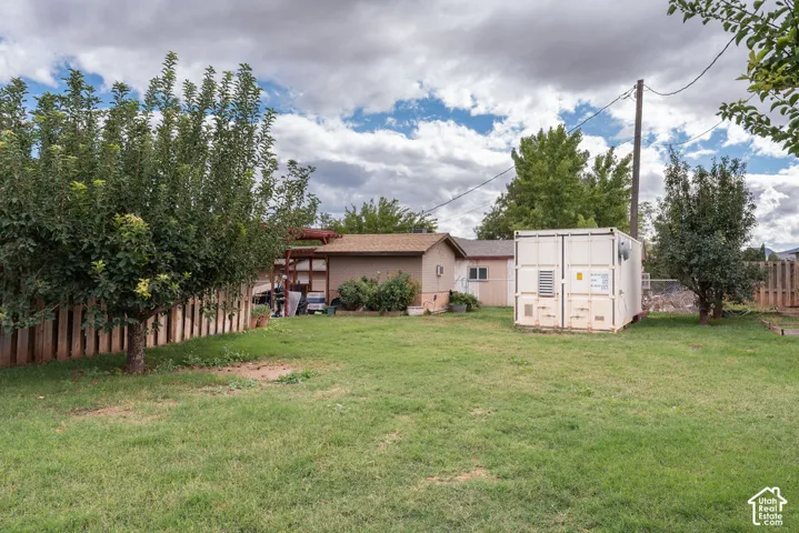 Expansive yard featuring a large grassy area, mature trees, and wood fencing