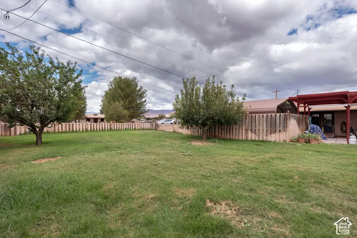 Expansive grassy backyard featuring a wood fence perimeter and mature trees