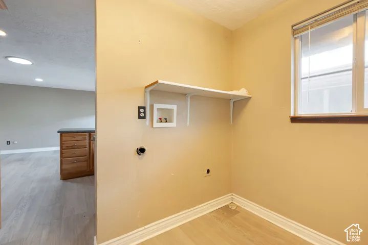 Laundry area with built-in shelving, a window, and wood-finish flooring