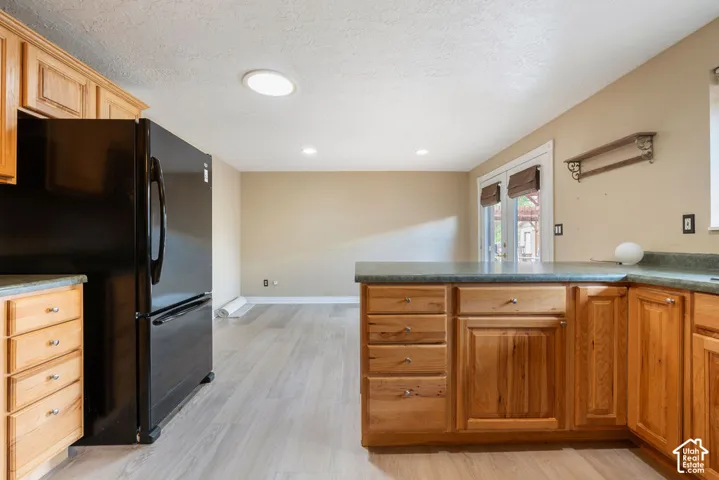 Kitchen featuring wood cabinetry, a corner counter, and wood-finish flooring