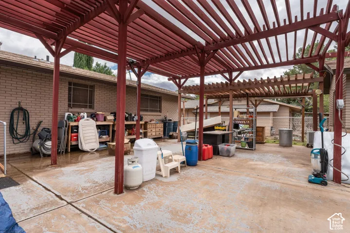 Expansive concrete patio featuring a red-stained wood pergola