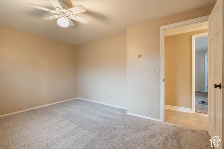 Carpeted room with a ceiling fan, light beige wall paint, and a white interior door
