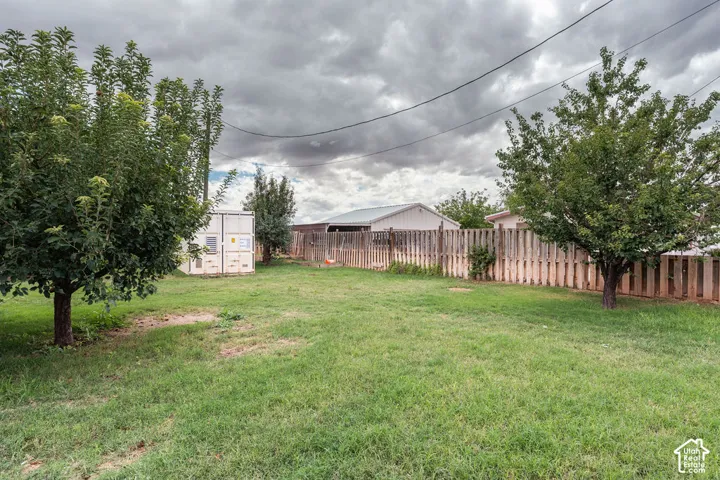 Expansive grassy yard with mature trees and a wood fence perimeter