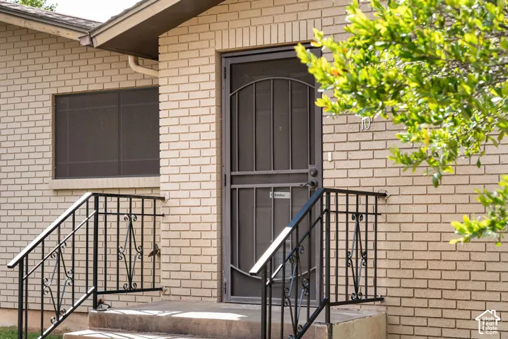 Brick exterior construction with an entry door, security screen door, and wrought iron railings