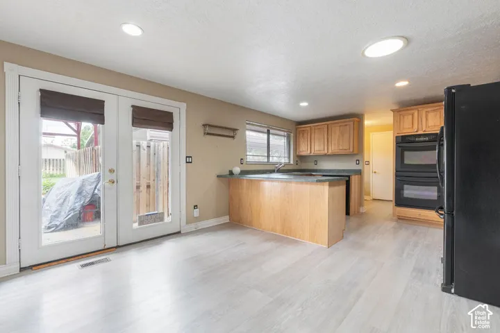 Kitchen featuring wood-finish cabinetry, double wall ovens, a skylight, recessed lighting, and light wood-finish flooring