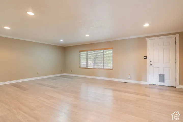 Spacious room with light wood-finish flooring, recessed lighting, and crown molding