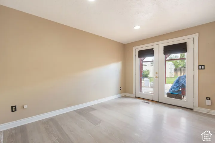 Wood-finish flooring, recessed lighting, and patio access through glass-paned French doors