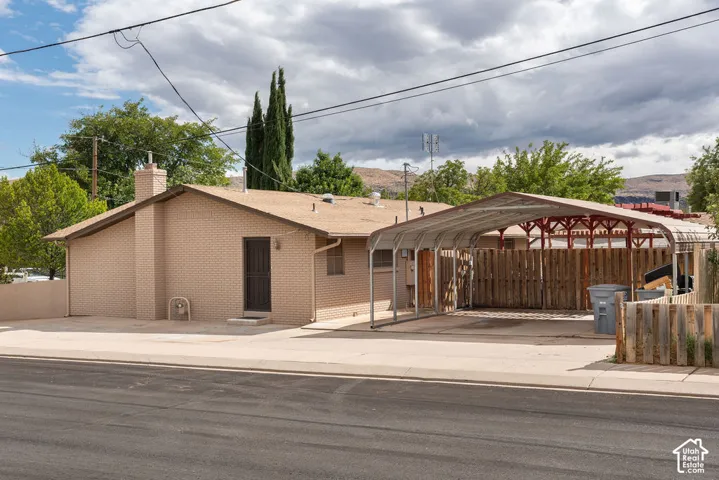Brick exterior, asphalt shingle roof, attached carport, wood fencing, and concrete driveway