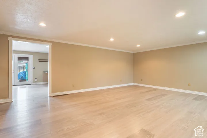 Expansive room featuring recessed lighting, wood-finish flooring, and crown molding