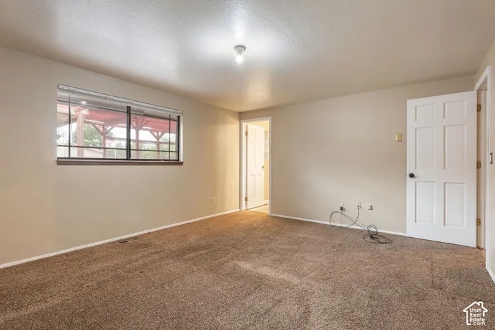 Carpeted interior space with a window featuring horizontal blinds