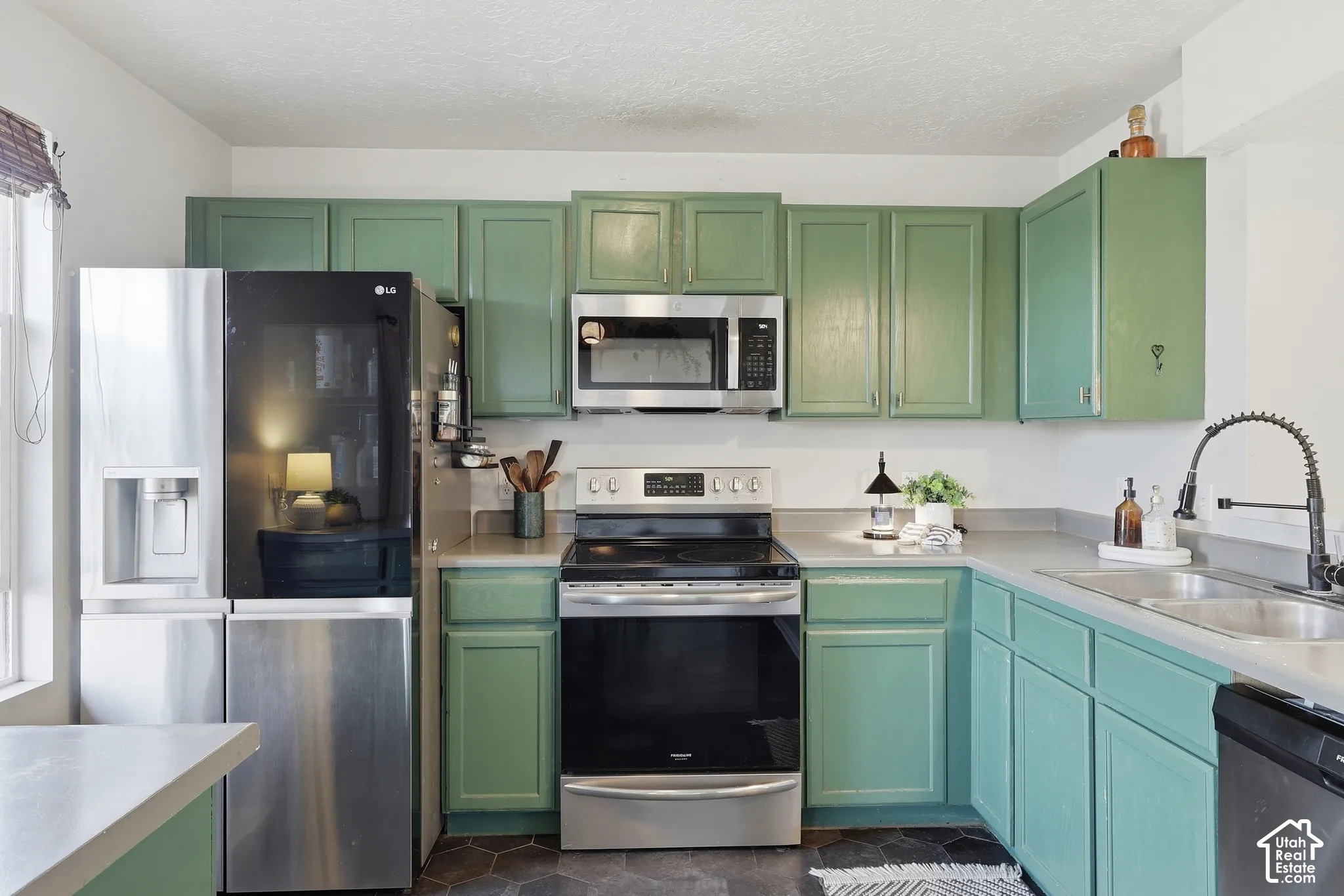 Kitchen featuring painted cabinetry, stainless steel appliances, a built-in microwave, and a double basin sink with a gooseneck faucet